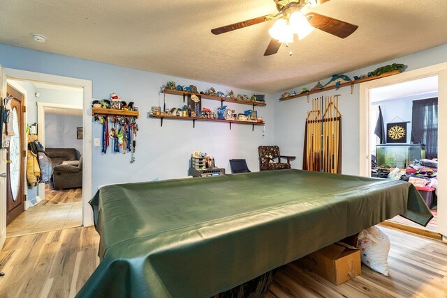 playroom with pool table, light wood-style flooring, a ceiling fan, and a textured ceiling
