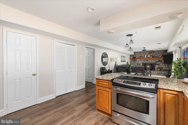  - kitchen featuring electric stove, brown cabinets, open floor plan, a stone fireplace, and light wood-type flooring