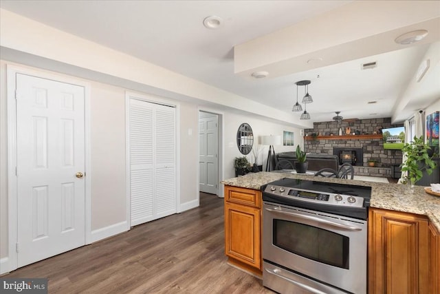  - kitchen with stainless steel electric stove, brown cabinets, a fireplace, and open floor plan