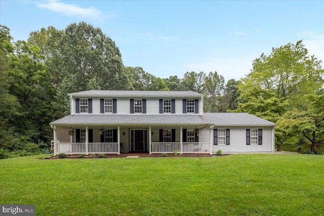  - view of front facade featuring covered porch, a front yard, and view of wooded area