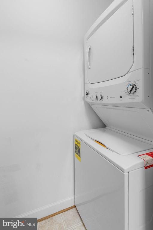  - washroom featuring stacked washing machine and dryer and light tile patterned flooring