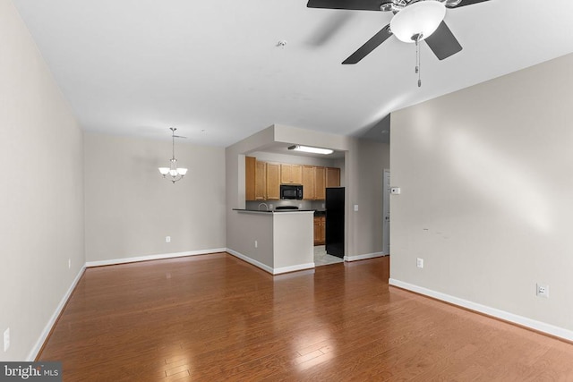  - unfurnished living room featuring a ceiling fan, wood finished floors, and a chandelier