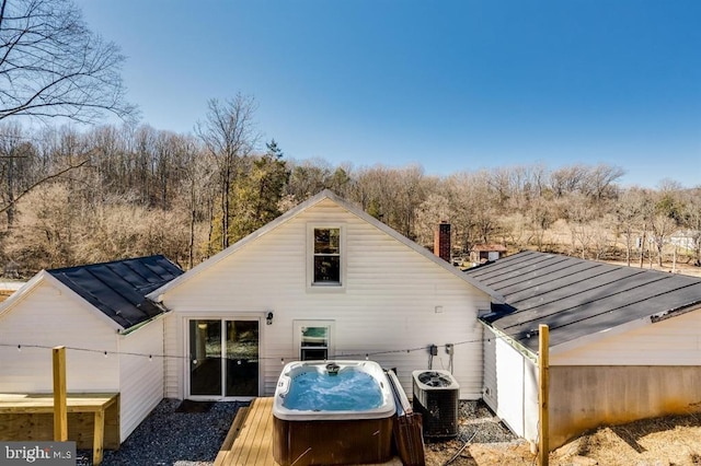 back of house with cooling unit, a hot tub, and a deck