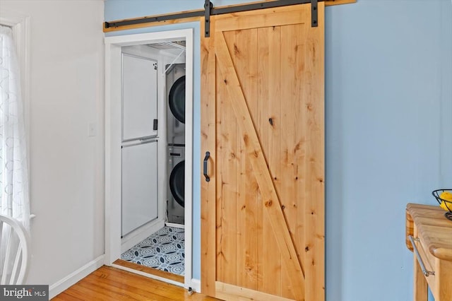 8952 Courthouse Rd, Spotsylvania, VA 22553 - laundry area featuring stacked washer / dryer, baseboards, wood finished floors, and a barn door