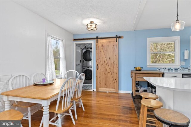 8952 Courthouse Rd, Spotsylvania, VA 22553 - dining area with stacked washing machine and dryer, a barn door, light wood-type flooring, healthy amount of natural light, and a textured ceiling