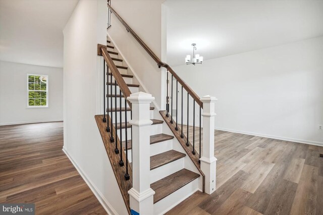  - stairs featuring wood finished floors, a chandelier, and baseboards
