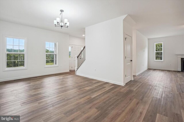  - unfurnished living room with a chandelier, stairway, healthy amount of natural light, and dark wood-style floors