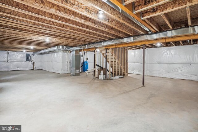  - unfinished below grade area with stairs, electric panel, heating unit, and a water pressure tank
