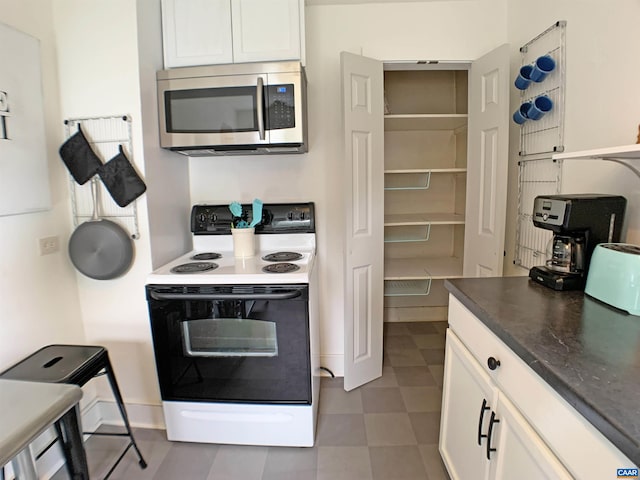 239 Shamrock Rd, Charlottesville, VA 22903 - kitchen with stainless steel microwave, electric stove, white cabinets, tile patterned floors, and dark countertops