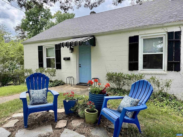 239 Shamrock Rd, Charlottesville, VA 22903 - property entrance featuring a shingled roof, concrete block siding, and a chimney