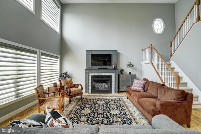 12400 Eustace Dr, Bumpass, VA 23024 - living area featuring a high ceiling, stairs, a glass covered fireplace, wood finished floors, and baseboards