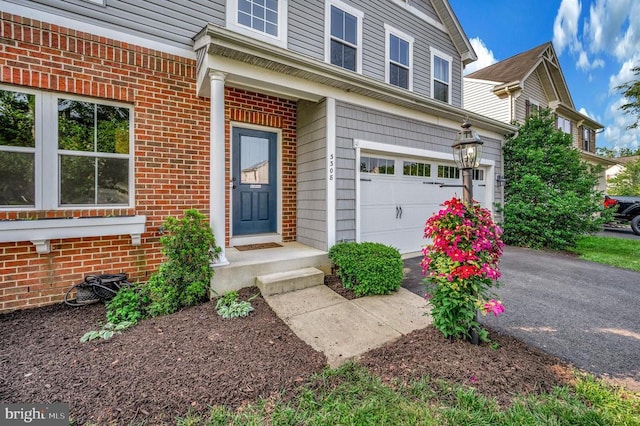  - property entrance with a garage, asphalt driveway, and brick siding