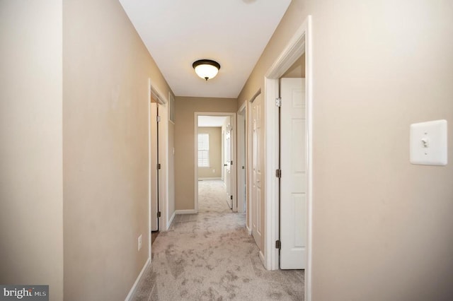  - hallway featuring light carpet and baseboards