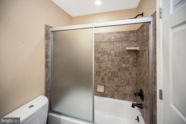  - bathroom featuring toilet and bath / shower combo with glass door