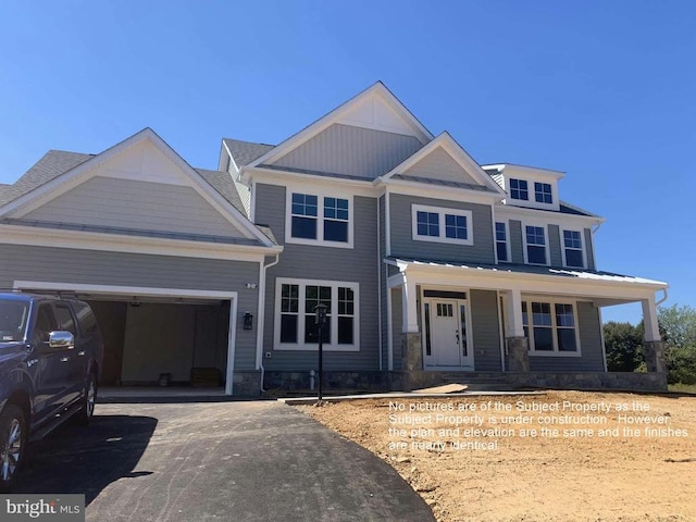 craftsman inspired home featuring driveway, a garage, a porch, and stone siding
