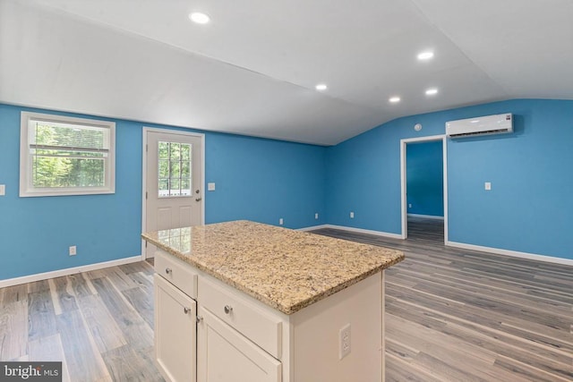 236 Laurel Dr, Madison, VA 22727 - kitchen featuring an AC wall unit, light wood-style flooring, white cabinets, vaulted ceiling, and a center island