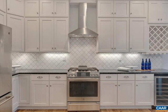 kitchen with beverage cooler, appliances with stainless steel finishes, tasteful backsplash, and wall chimney exhaust hood