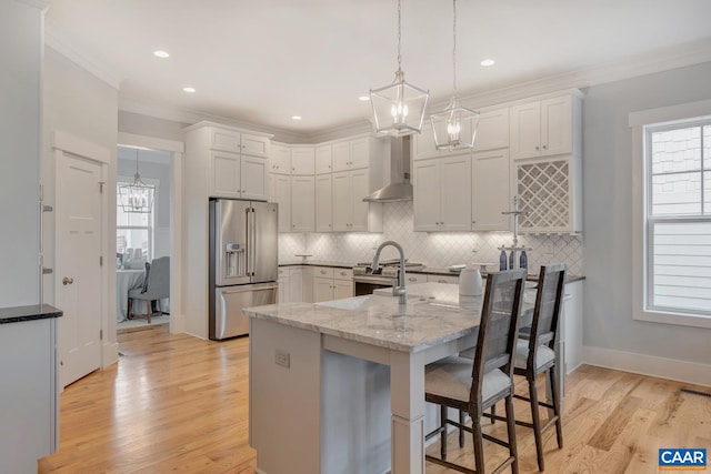 kitchen with a notable chandelier, light stone countertops, premium appliances, decorative backsplash, and wall chimney exhaust hood