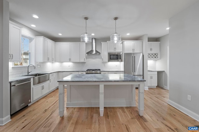 kitchen with backsplash, wall chimney range hood, stainless steel appliances, and a sink