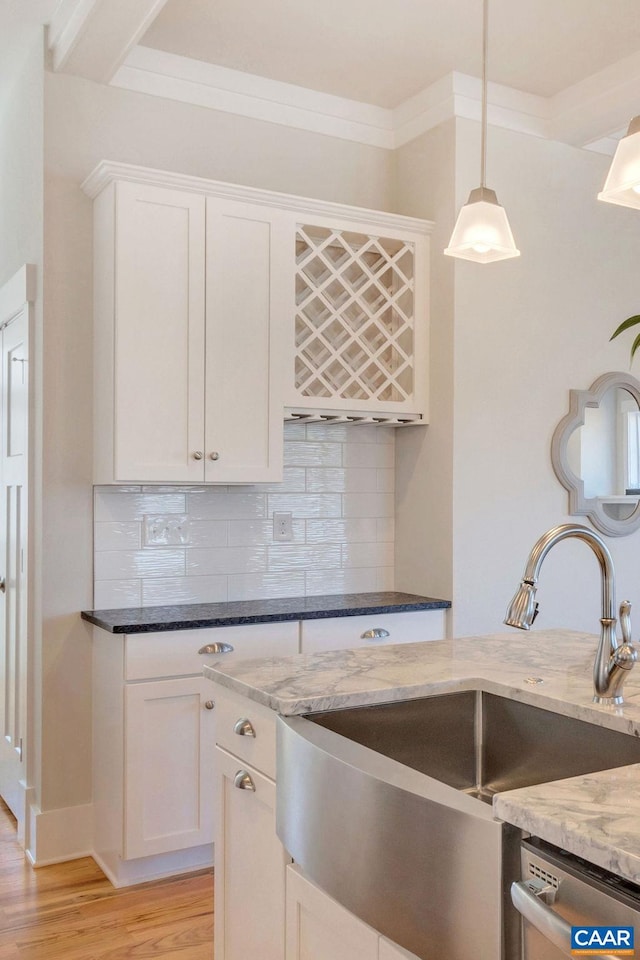 kitchen featuring a sink, light wood-style floors, white cabinets, and dark stone counters