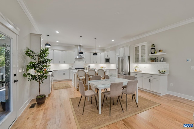 dining area with ornamental molding, light wood-style flooring, and recessed lighting