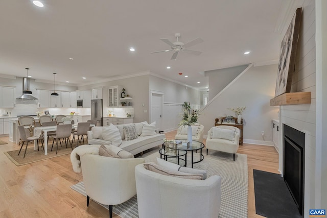living area with light wood-style flooring, recessed lighting, baseboards, ceiling fan, and a large fireplace