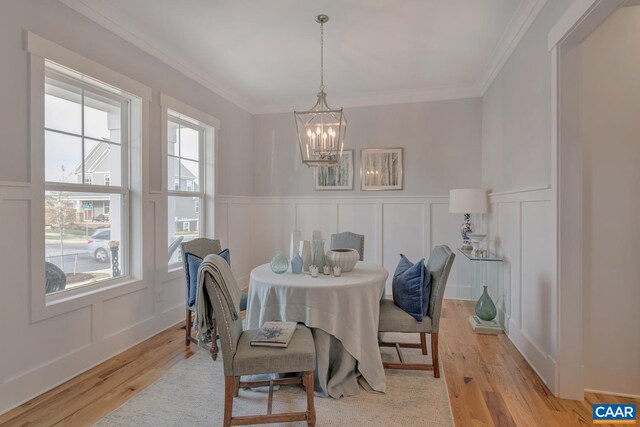 dining room featuring light wood finished floors, a decorative wall, and a notable chandelier