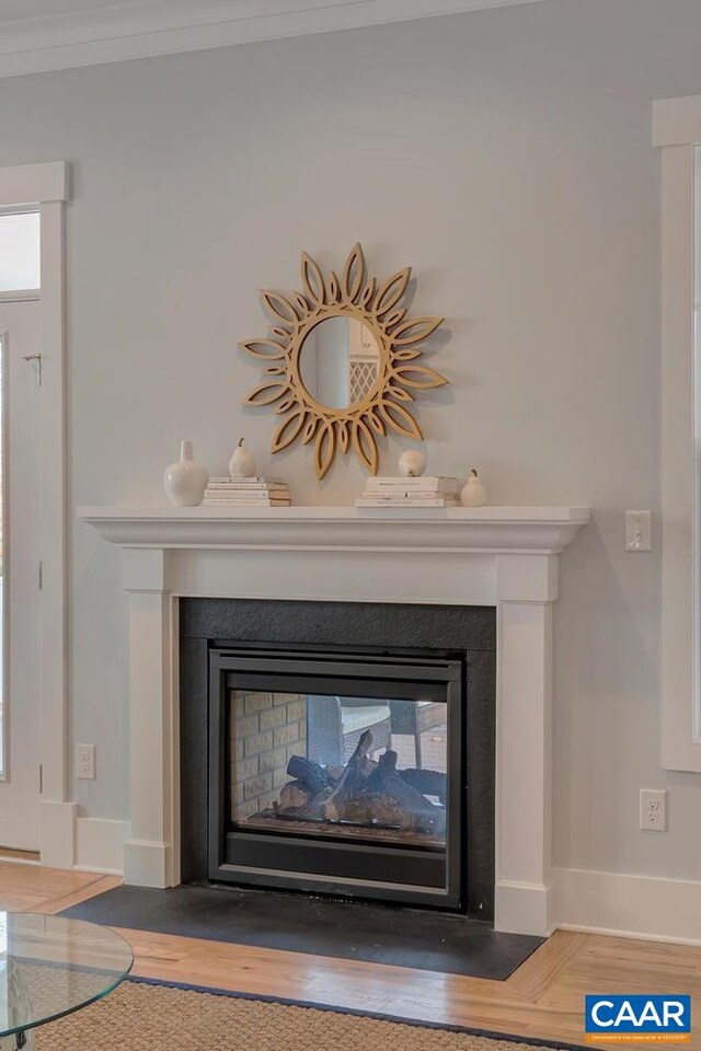 interior details with a multi sided fireplace, baseboards, wood finished floors, and ornamental molding