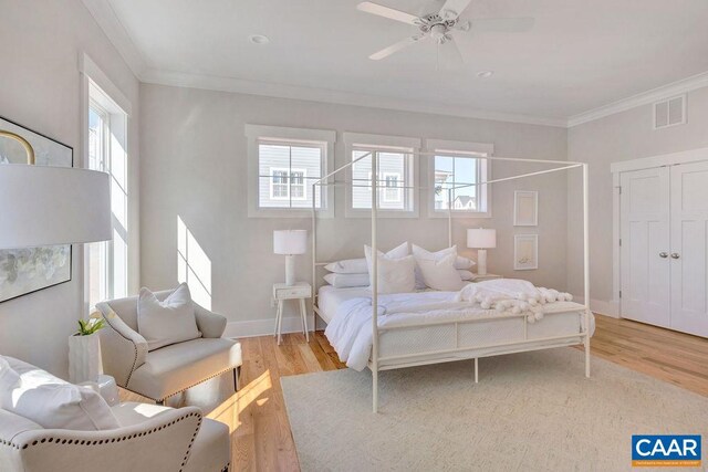bedroom with light wood-style flooring, visible vents, baseboards, ceiling fan, and ornamental molding