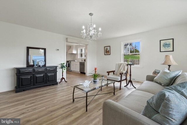 living room with a chandelier, light wood finished floors, and baseboards