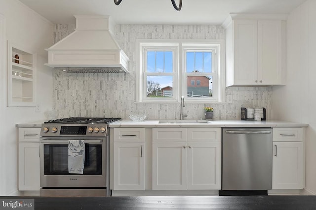 kitchen featuring appliances with stainless steel finishes, custom range hood, a sink, white cabinetry, and decorative backsplash