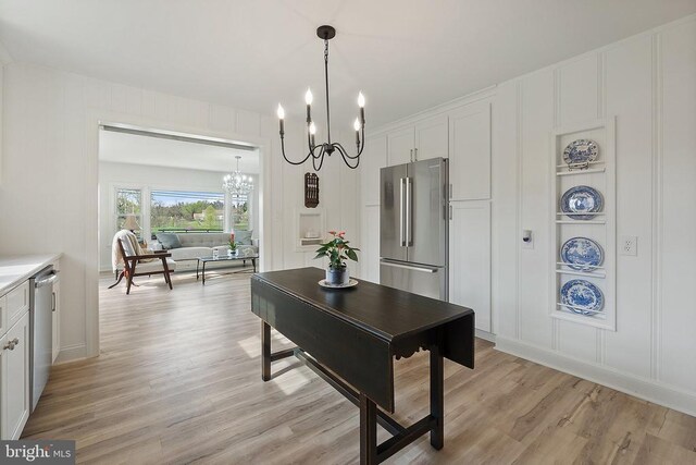 dining area with a chandelier, a decorative wall, light wood-type flooring, and built in shelves