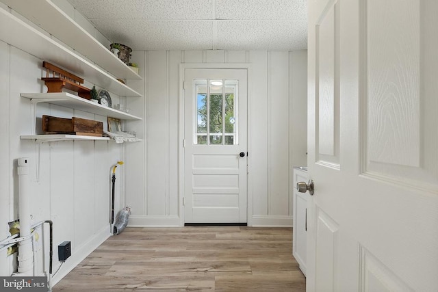 clothes washing area featuring light wood-style floors and a decorative wall