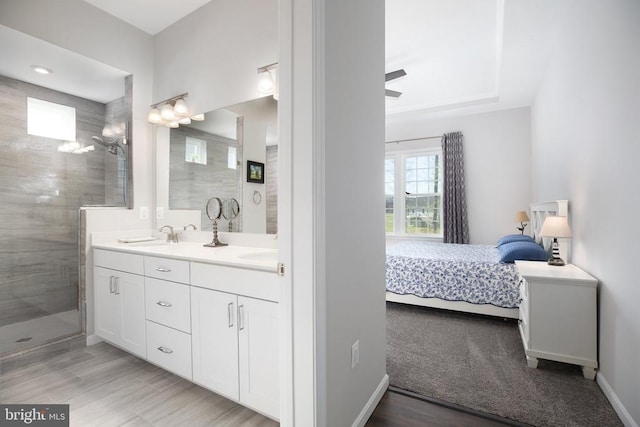 full bathroom with ensuite bath, a shower stall, double vanity, baseboards, and wood finished floors