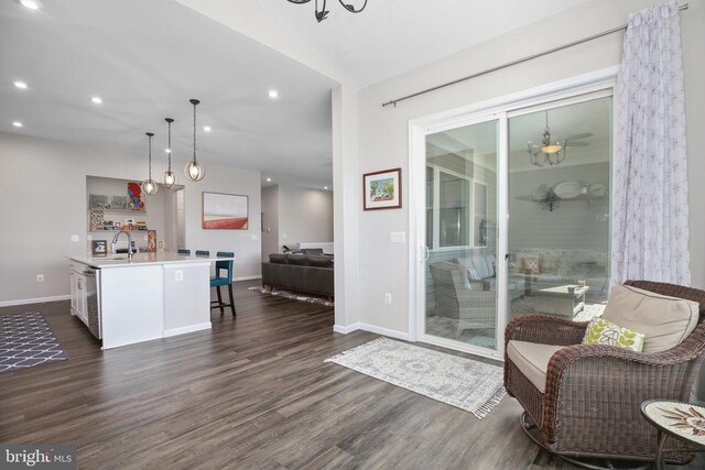 kitchen with open floor plan, dark wood-style floors, light countertops, an island with sink, and pendant lighting