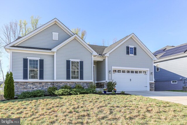 traditional-style home with stone siding, driveway, a front lawn, and an attached garage
