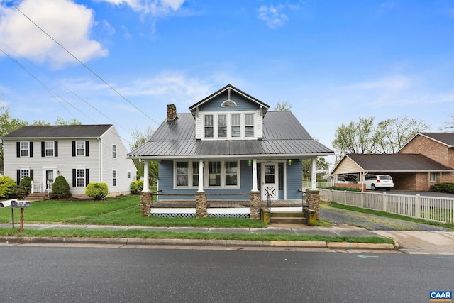 bungalow-style home featuring a chimney, fence, metal roof, a porch, and a front lawn