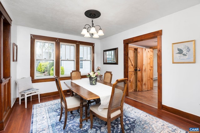 dining area featuring a chandelier, baseboards, and wood finished floors
