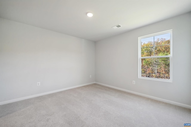 empty room featuring light colored carpet, visible vents, and baseboards