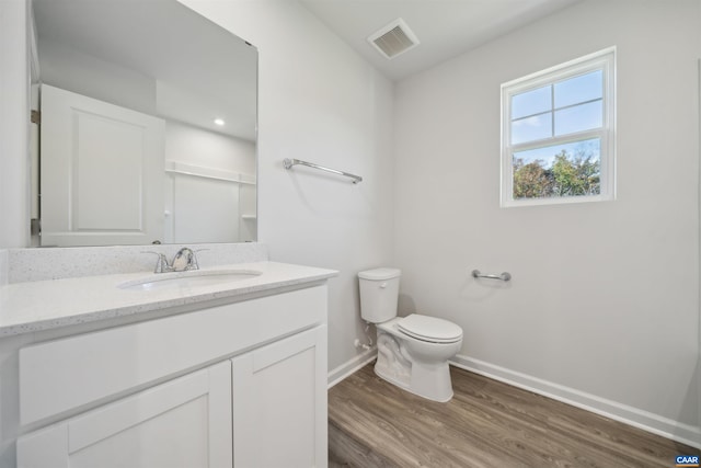bathroom featuring toilet, wood finished floors, vanity, visible vents, and baseboards