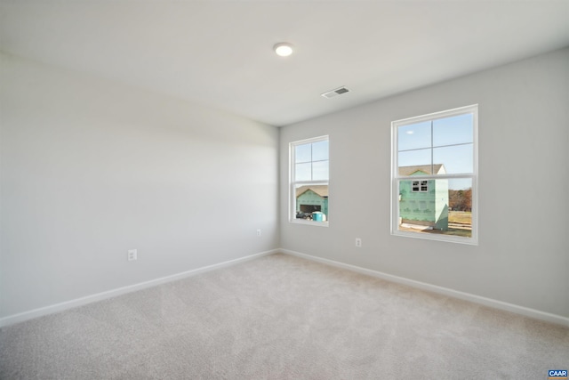spare room featuring light colored carpet, baseboards, and visible vents