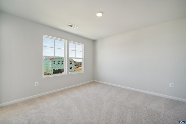 empty room featuring light carpet, baseboards, and visible vents