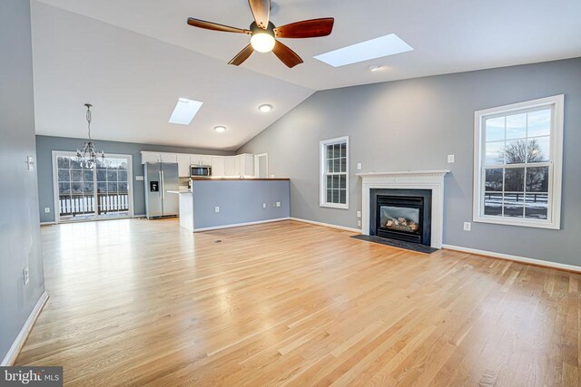 unfurnished living room with plenty of natural light, lofted ceiling with skylight, and light wood-type flooring