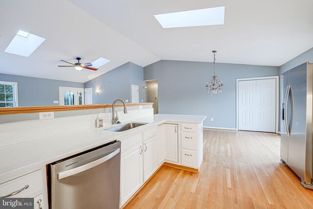 kitchen featuring sink, white cabinetry, hanging light fixtures, stainless steel appliances, and light wood-type flooring