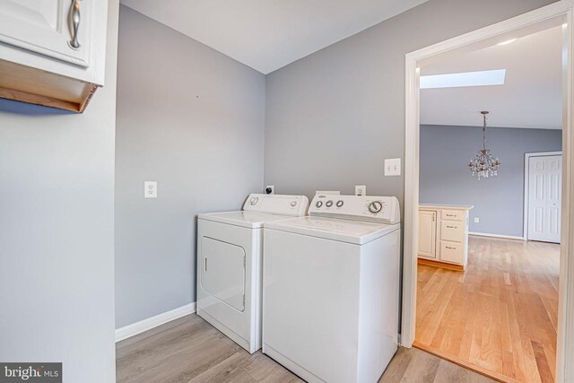 laundry room with an inviting chandelier, cabinets, washer and clothes dryer, and light hardwood / wood-style flooring