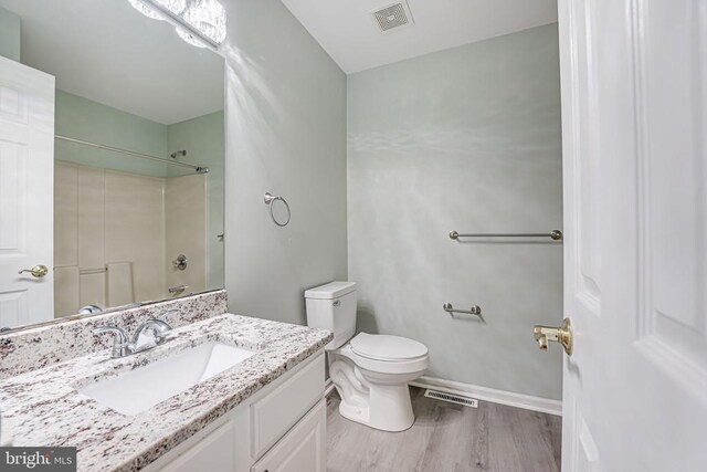 full bathroom featuring vanity, hardwood / wood-style flooring, bathing tub / shower combination, and toilet