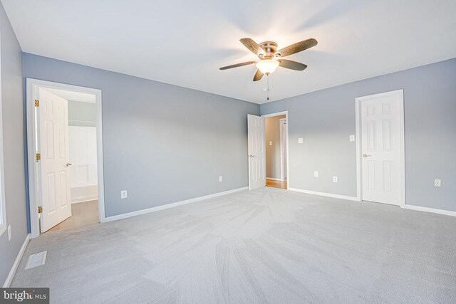 unfurnished bedroom with ensuite bathroom, light colored carpet, and ceiling fan