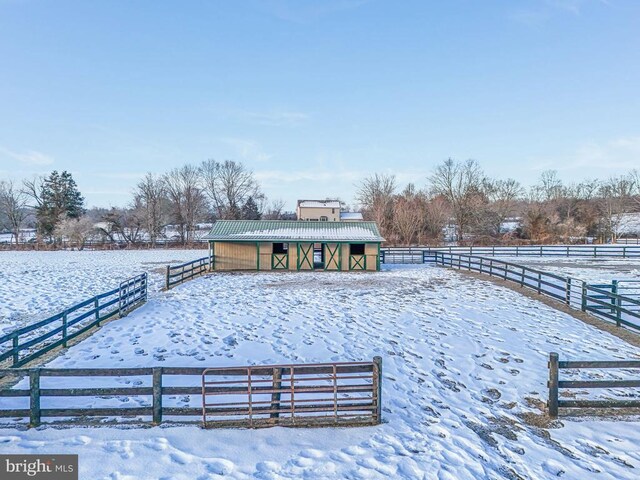 yard layered in snow with a rural view and an outdoor structure