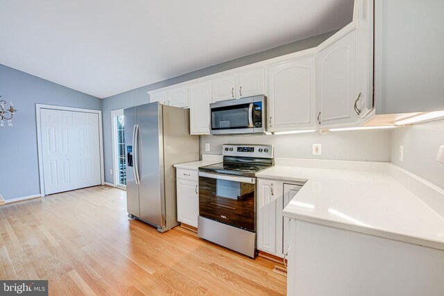 kitchen with lofted ceiling, light wood-type flooring, white cabinets, and appliances with stainless steel finishes