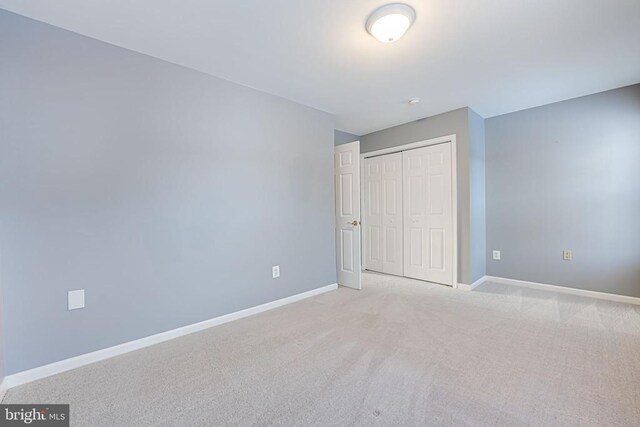 unfurnished bedroom featuring light colored carpet and a closet